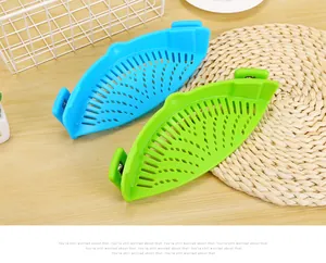 Detailed view of blue and green silicone clip-on pot strainers on a kitchen wooden table.