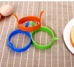 Vue détaillée de trois anneaux d'oeuf en silicone colorés sur une nappe à carreaux