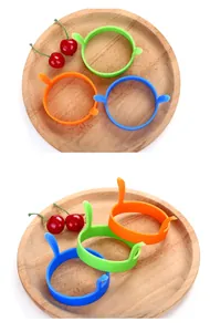 Vue détaillée de trois anneaux à œufs en silicone antiadhésifs colorés sur un plateau.