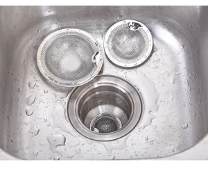 Stainless steel sink strainers placed in a kitchen sink with water droplets, detail view.