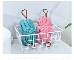 Dettaglio di spugne da bagno in rete morbida colorata in un cesto contenitore bianco