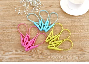 Plastic clothespins with hanging loops in pink, blue and yellow shown on wood surface
