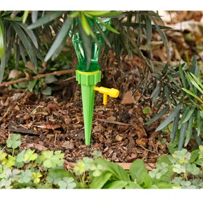 Automatischer Pflanzenbewässerer mit einstellbarem Regelventil im Gartenboden platziert.