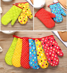 Varios guantes de horno coloridos con lunares resistentes al calor sobre madera.