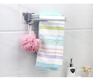 Dettaglio di un portasciugamani rotante grigio montato a parete in bagno con accessori