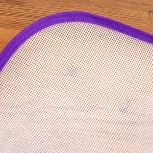 Close-up of a white mesh ironing insulation mat with durable purple fabric edge