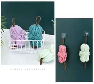 Spugne da bagno colorate in rete morbida esposte in un cesto e appese ai ganci