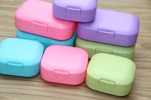 Close-up of colorful portable travel soap boxes with secure lids on wood surface