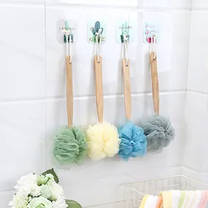 Long-handled bath sponges in four colors hanging on a white bathroom wall