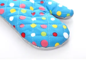 Primer plano de un guante para horno grueso con lunares de colores para hornear.