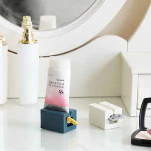 Manual tube squeezer holder for toothpaste and facial cleanser in a modern bathroom setting