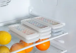 Multiple mini spherical silicone ice ball trays stacked neatly inside a refrigerator shelf