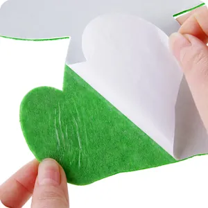 Green felt toilet deodorizing sticker with adhesive backing being peeled for application.