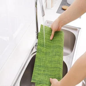 Close-up of a green textured placemat being rinsed under water in a sink