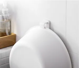 Primer plano de un gancho de plástico blanco para baño que sostiene un lavabo en la pared.