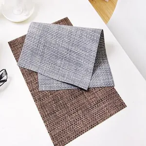 Close-up detail of woven heat-resistant placemats in brown and grey for dining table.