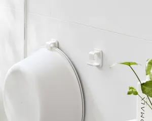 Detalle de ganchos adhesivos de plástico blanco para lavabos montados en pared de baño