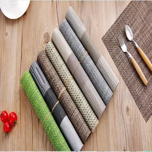 Various rolled woven heat-resistant placemats arranged on a rustic wooden table