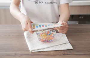 Detail of hands using a white silicone spherical mold to release colorful gel beads.