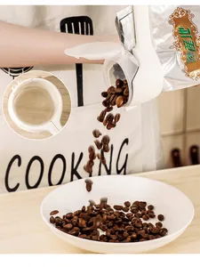 Detail shot of a white plastic food sealer clip with a pouring spout dispensing coffee beans