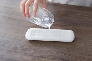 Detail shot of pouring water into a white spherical silicone mini ice ball tray
