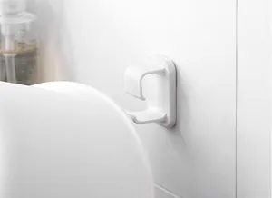 Detalle de gancho de plástico blanco para organizar lavabos en la pared del baño