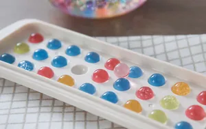 Close-up of a white silicone mold filled with colorful translucent resin spheres.