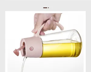 Close-up of glass oil dispenser pouring golden liquid with pink ergonomic handle