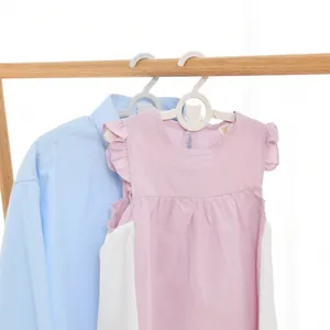Cintres en plastique réglables pour enfants et bébés sur un portant à vêtements en bois.