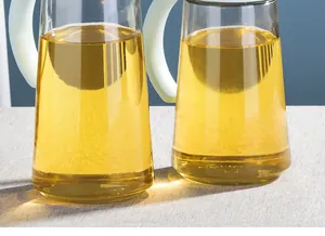 Detailed macro view of two glass oil pitchers with light blue handles on a table.