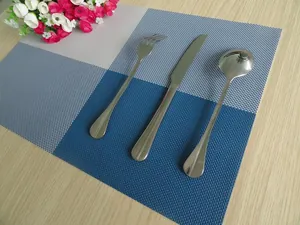 Blue and grey grid PVC placemat with stainless steel cutlery on a wooden table.