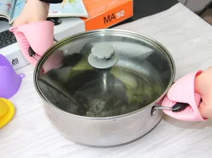 Detailopname van hittebestendige roze siliconen ovenwanten bij een kookpan