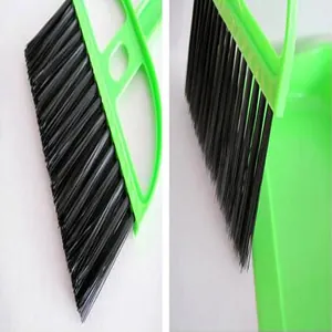 Close-up of black bristles and green plastic handle of mini desktop cleaning broom set