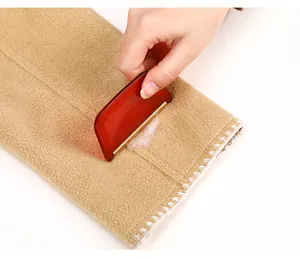 Detailed macro view showing a manual lint remover efficiently scraping fuzz off a wool coat fabric