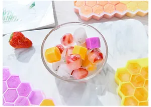 Macro detail of fruit-filled ice cubes in a clear bowl with silicone honeycomb trays