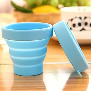 Light blue food-grade silicone folding cup with lid shown in a home kitchen setting