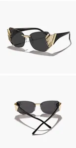 Detail view of modern rimless sunglasses with ornate gold wing accents and black lenses