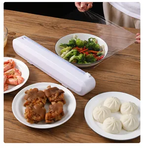 White plastic cling wrap cutter used for covering a bowl of fresh vegetables in a kitchen