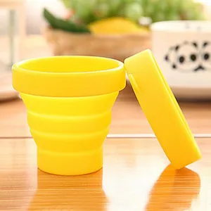 Close-up of a yellow silicone collapsible travel cup and lid on a wooden surface