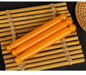 Set of three amber-colored facial massage sticks displayed on a rustic bamboo mat
