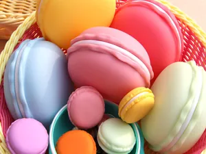 Colorful macaron shaped jewelry storage boxes in various sizes displayed in a woven basket.