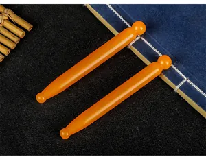 Detail view of two amber-colored resin acupoint massage sticks on a vintage background.