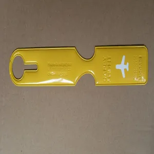 Detail view of a long yellow luggage tag with airplane icon and travel slogans