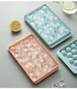 Top view of blue and orange round ice ball trays with clear ice spheres and lemons