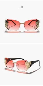 Close-up detail of rimless gradient sunglasses featuring intricate golden wing accents