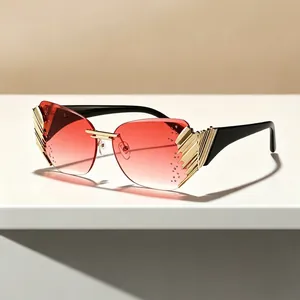 Modern rimless sunglasses with red gradient lenses and gold wing-shaped metal accents