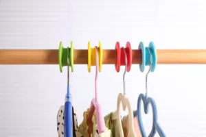 Gros plan de crochets d'espacement colorés pour cintres sur une barre en bois