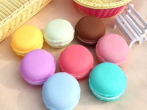 Macro detail of colorful macaron-shaped jewelry storage boxes on sandy background.