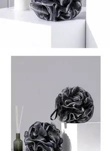 Detailed close-up of large dark grey bath loofahs with mesh texture on white blocks