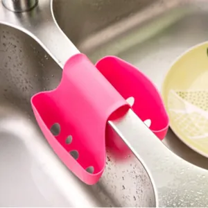 Pink saddle-style silicone sink sponge holder with drainage holes for kitchen storage